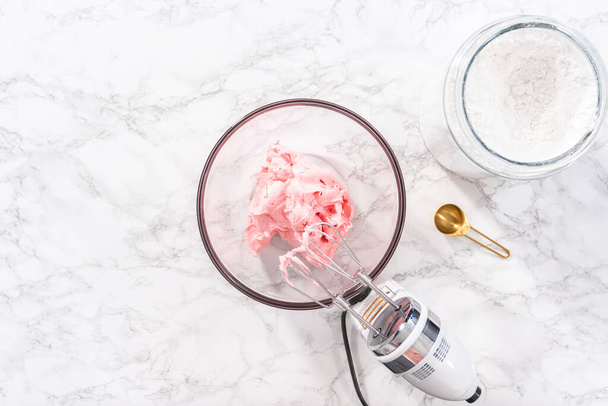 Flat lay. Mixing in store-bought buttercream frosting in a glass mixing bowl. - Valokuva, kuva