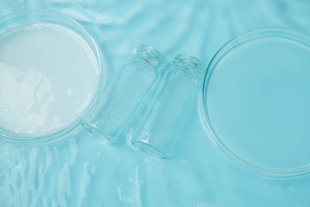 Set of laboratory utensils empty Petri dish, flasks, jars on the background of blue water - Foto, imagen
