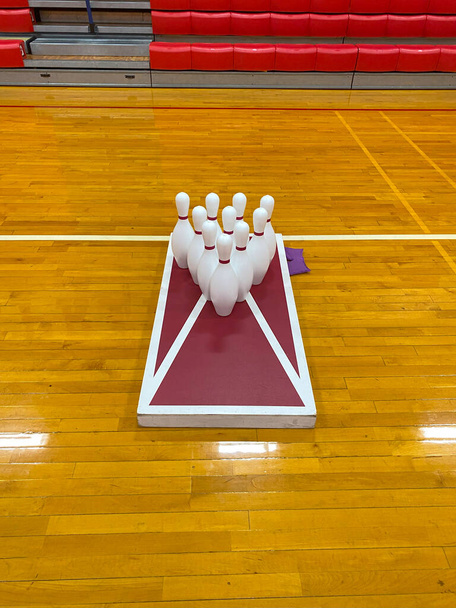 Een zelfgemaakt maïsgat spel met tien bowling pinnen op de top in een middelbare school gym. - Foto, afbeelding