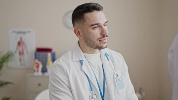 Mladý hispánec muž lékař usmívá sebevědomě stojí na klinice - Záběry, video