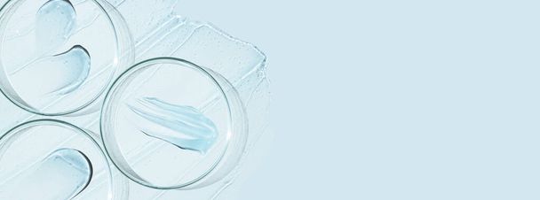 Pratos de Petri e gotas e pomadas de gel transparente ou soro em um fundo azul. Banner com espaço vazio para publicidade. - Foto, Imagem
