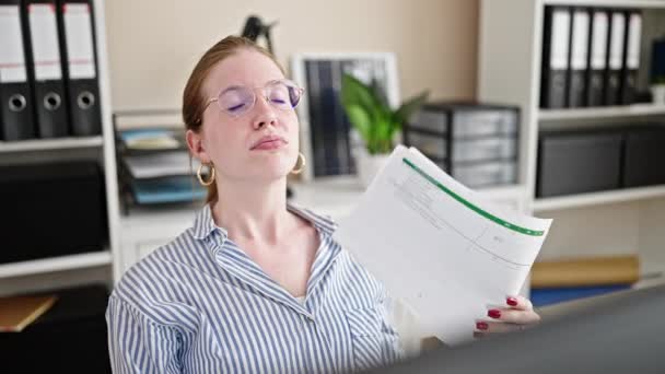 Jeune femme blonde femme d'affaires utilisant des documents comme ventilateur de main au bureau - Séquence, vidéo