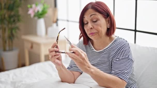 Keski-ikäinen nainen ottaa lasit pois makaa sängyssä nukkumaan makuuhuoneessa - Materiaali, video