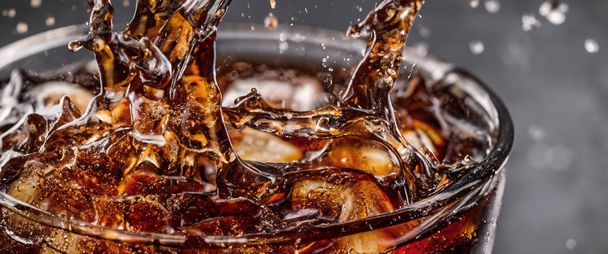 Pouring of Cola and Ice. Cola soda and ice splashing fizzing or floating up to top of surface. Close up of ice in cola water. Texture of carbonate drink with bubbles in glass. Cold drink background - Photo, Image