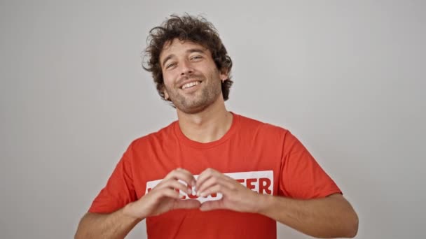 Νεαρός Ισπανός ακτιβιστής φορώντας στολή εθελοντή να κάνει χειρονομία καρδιάς αγγίζοντας το στήθος πάνω από απομονωμένο λευκό φόντο - Πλάνα, βίντεο