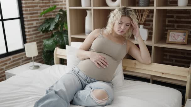 Νεαρή έγκυος γυναίκα αγγίζοντας την κοιλιά με άγχος έκφραση στο υπνοδωμάτιο - Πλάνα, βίντεο