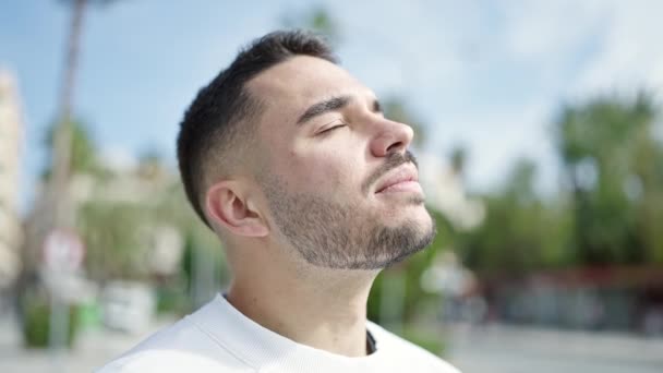 Jonge Spaanse man ademt met gesloten ogen op straat - Video