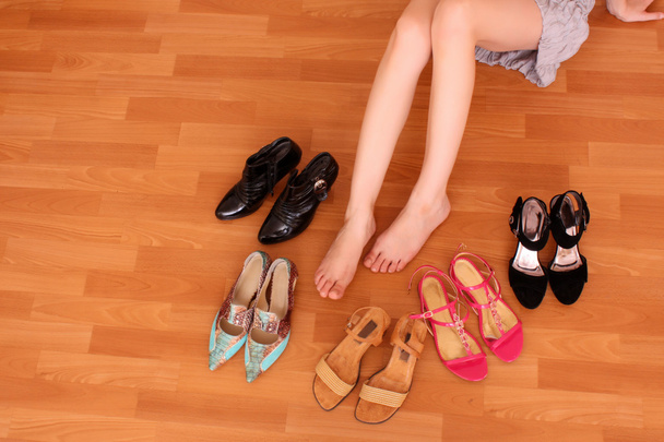 Closeup of a woman leg on floor and many shoes around - 写真・画像