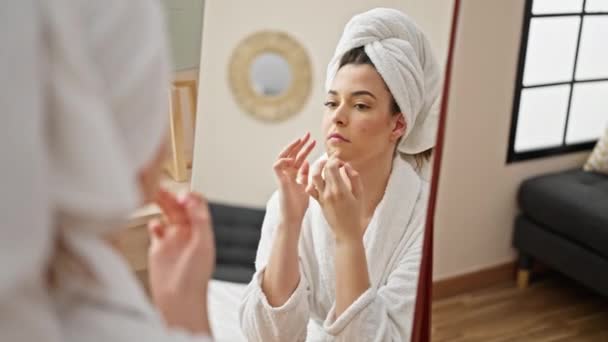 Fiatal gyönyörű spanyol nő fürdőköpenyt visel megható arc néz tükör a hálószobában - Felvétel, videó