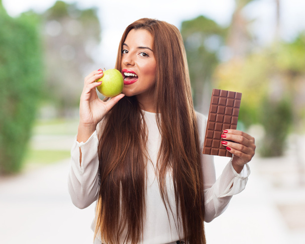 Mujer comiendo una manzana en lugar de un chocolate
 - Foto, imagen