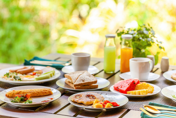 Morning breakfast at tropical outdoor restaurant in Asian resort. Enjoy a tasty and nutritious meal with pancakes, tropical fruit, and a glass of orange juices. Concept of a Thailand vacation. - Фото, зображення