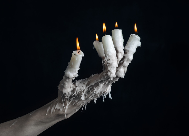 Halloween theme: on the hand wearing a candle and dripping melted wax on black isolated background - Zdjęcie, obraz