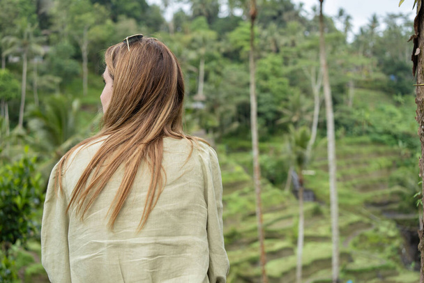 A back view of woman enjoying view of green rice fields. Ubud. Bali, Indonesia . Travel concept. - Foto, Bild