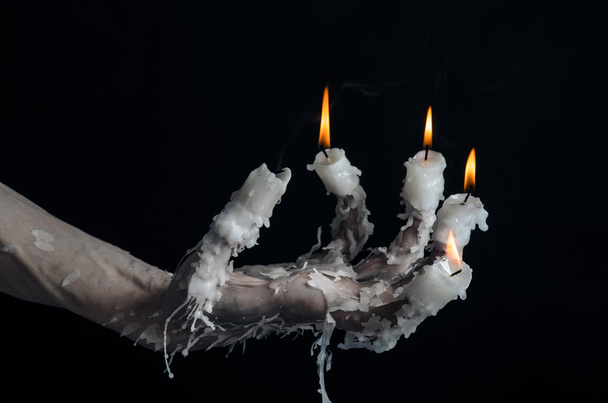 Halloween theme: on the hand wearing a candle and dripping melted wax on black isolated background - Foto, immagini