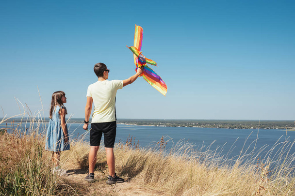Children play in nature, launching a kite into the sky. - Foto, afbeelding