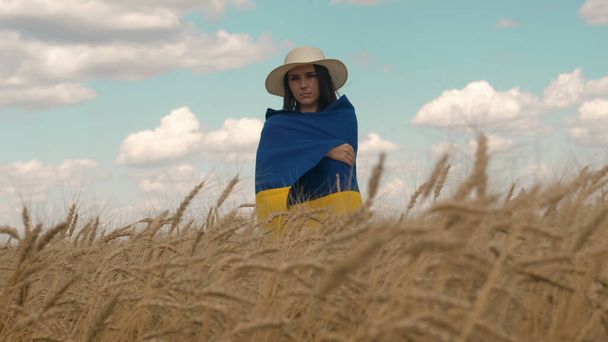 Portret van de Oekraïense patriottische vrouw staat in een tarweveld met blauw-gele vlag van Oekraïne - Foto, afbeelding