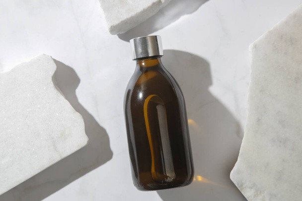 Mermer zemin üzerinde kahverengi cam kozmetik şişe - Fotoğraf, Görsel