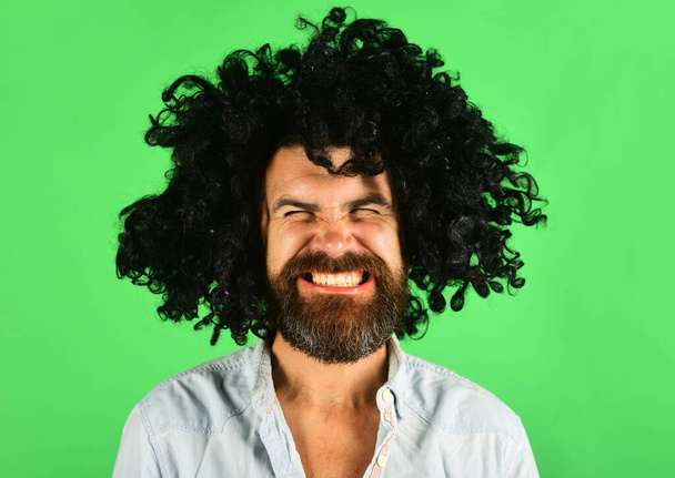 Funny man in black wig. Man with beard and mustache in curly periwig. Bearded hipster in black curly afro wig. Barbershop. Stylish guy with black hair. Bearded man in black curly afro style hair wig - Photo, Image
