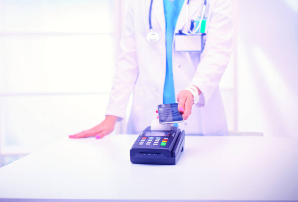 Doctor is holding payment terminal in hands. Paying for health care. Doctor. - Φωτογραφία, εικόνα