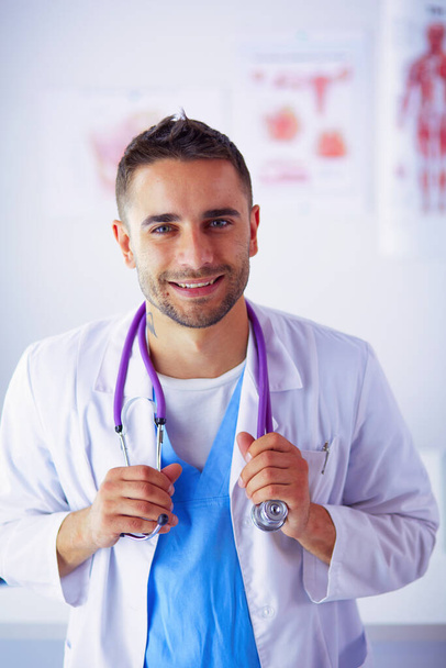 Young and confident male doctor portrait standing in medical office - Fotoğraf, Görsel