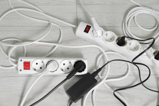 Power strips with different electrical plugs on white floor, flat lay - Fotografie, Obrázek