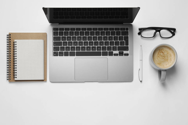 Modern laptop, notebooks, glasses and cup of coffee on white table, flat lay. Space for text - Fotoğraf, Görsel