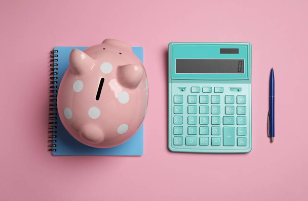 Calculator, piggy bank, notebook and pen on pink background, flat lay - Φωτογραφία, εικόνα