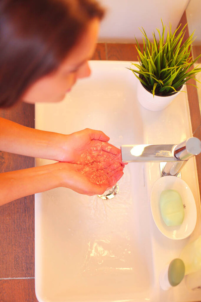 Young woman washing her face with clean water in bathroom. - Photo, image