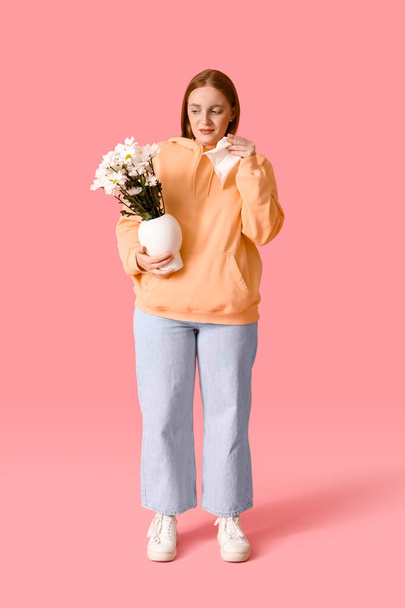 Allergic young woman with flowers and tissue on pink background - Foto, afbeelding