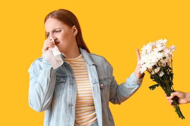 Jeune femme allergique et la main avec des fleurs sur fond jaune - Photo, image
