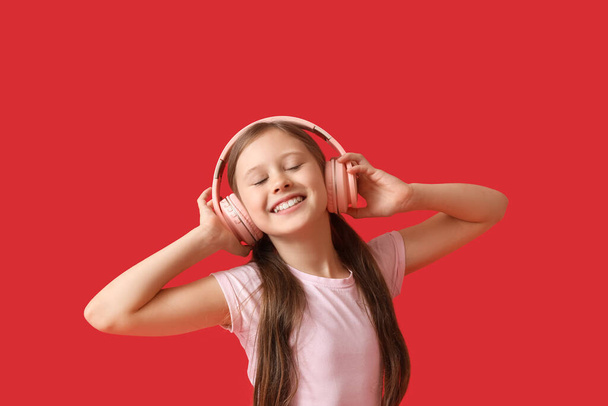 Little girl in headphones on red background - Photo, Image