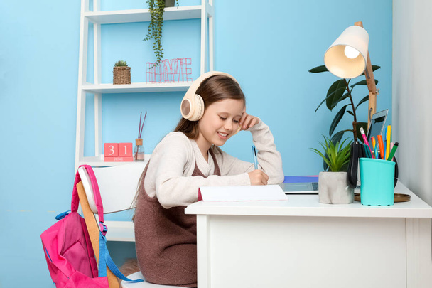 Kislány fülhallgatóban otthon tanul. - Fotó, kép