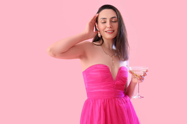 Hermosa mujer con martini sobre fondo rosa - Foto, Imagen