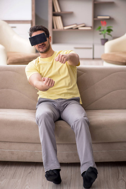 Young male student enjoying virtual glasses at home - Fotó, kép