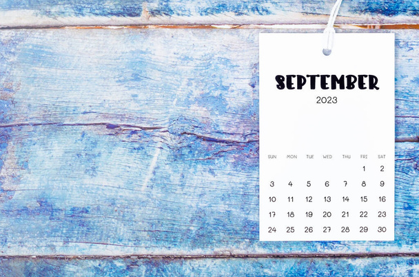 September 2023 calendar page hanged with white rope on old blue wooden background. - Foto, Imagem