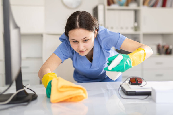 Cleaning company employee wipes dust from table in office - Foto, Imagem