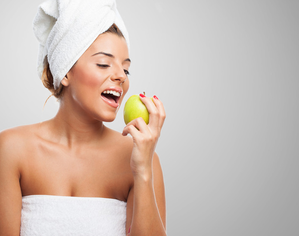 Woman eating an apple after a bath - Фото, изображение
