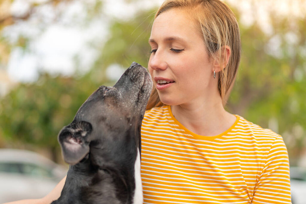 Jeune femme blonde avec son adorable chien noir à l'extérieur - Photo, image