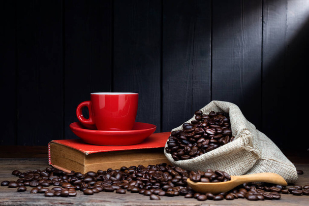 Café preto ou chá quente em uma xícara de café expresso cappuccino, café da manhã com grãos de café em uma mesa de madeira Isolado em um fundo escuro - Foto, Imagem