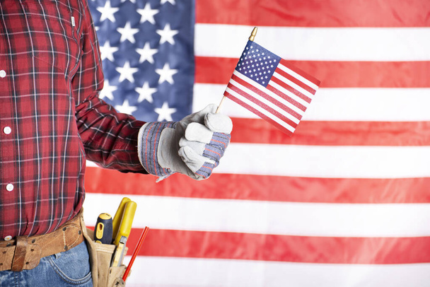 Carpenter in protective gloves and toolbelt with us flag labor day background - Fotografie, Obrázek