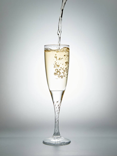 Шампанське вливається в келих на сірому фоні, студійний знімок - Фото, зображення