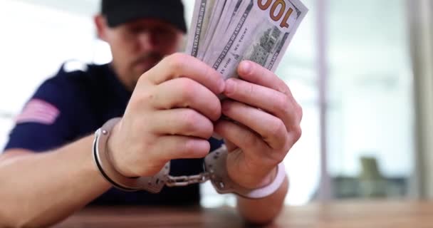 Un policier corrompu menotté tient un tas de dollars en gros plan. Système de corruption policière - Séquence, vidéo