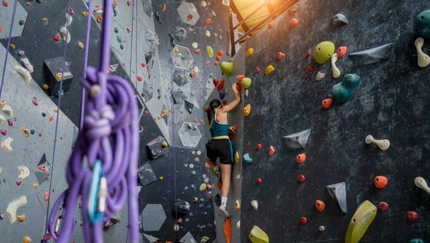 Strong woman on artificial climbing wall with colorful grips and ropes. - Foto, Imagem