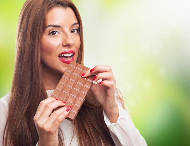 Menina bonita mordendo uma barra de chocolate
 - Foto, Imagem