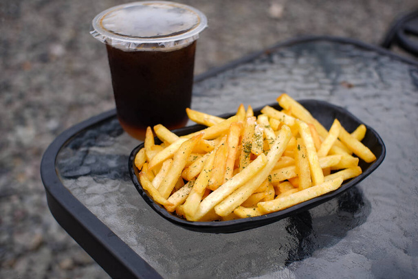 Delicious French Fries Presented on a Black Plate on a Glass Table - Photo, Image
