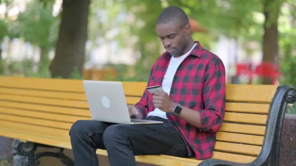 Giovane uomo africano che ha problemi di pagamento online sul computer portatile all'aperto - Filmati, video