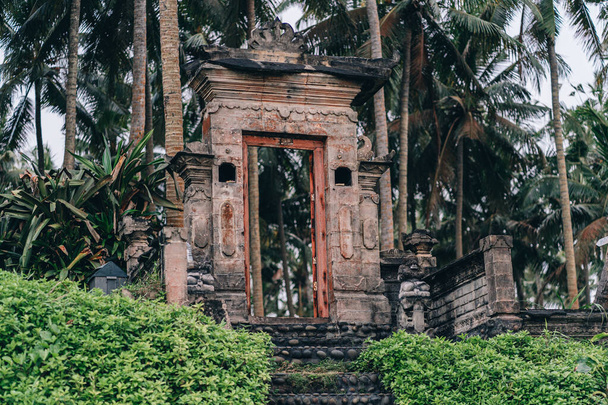 Puertas de piedra del templo en la selva tropical. Antiguas ruinas rodeadas de palmeras exóticas - Foto, Imagen