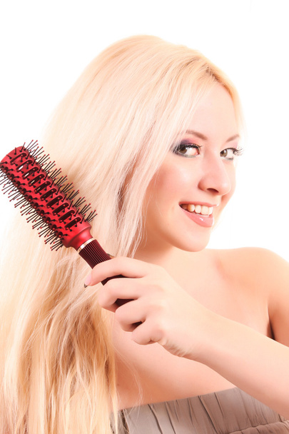 Beautiful young blonde woman brushing her long hair - Фото, изображение