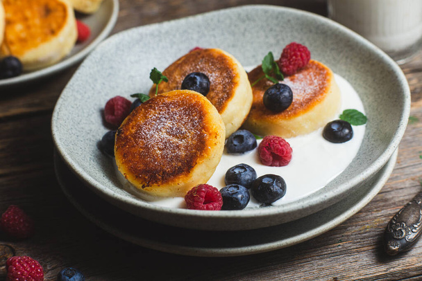 Cottage cheese pancakes with creamy sauce, raspberries and blueberries - Photo, Image