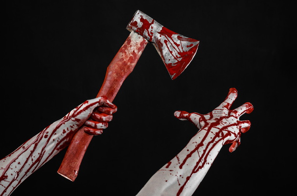 Bloody Halloween theme: bloody hand holding a bloody butcher's ax isolated on black background in studio - 写真・画像